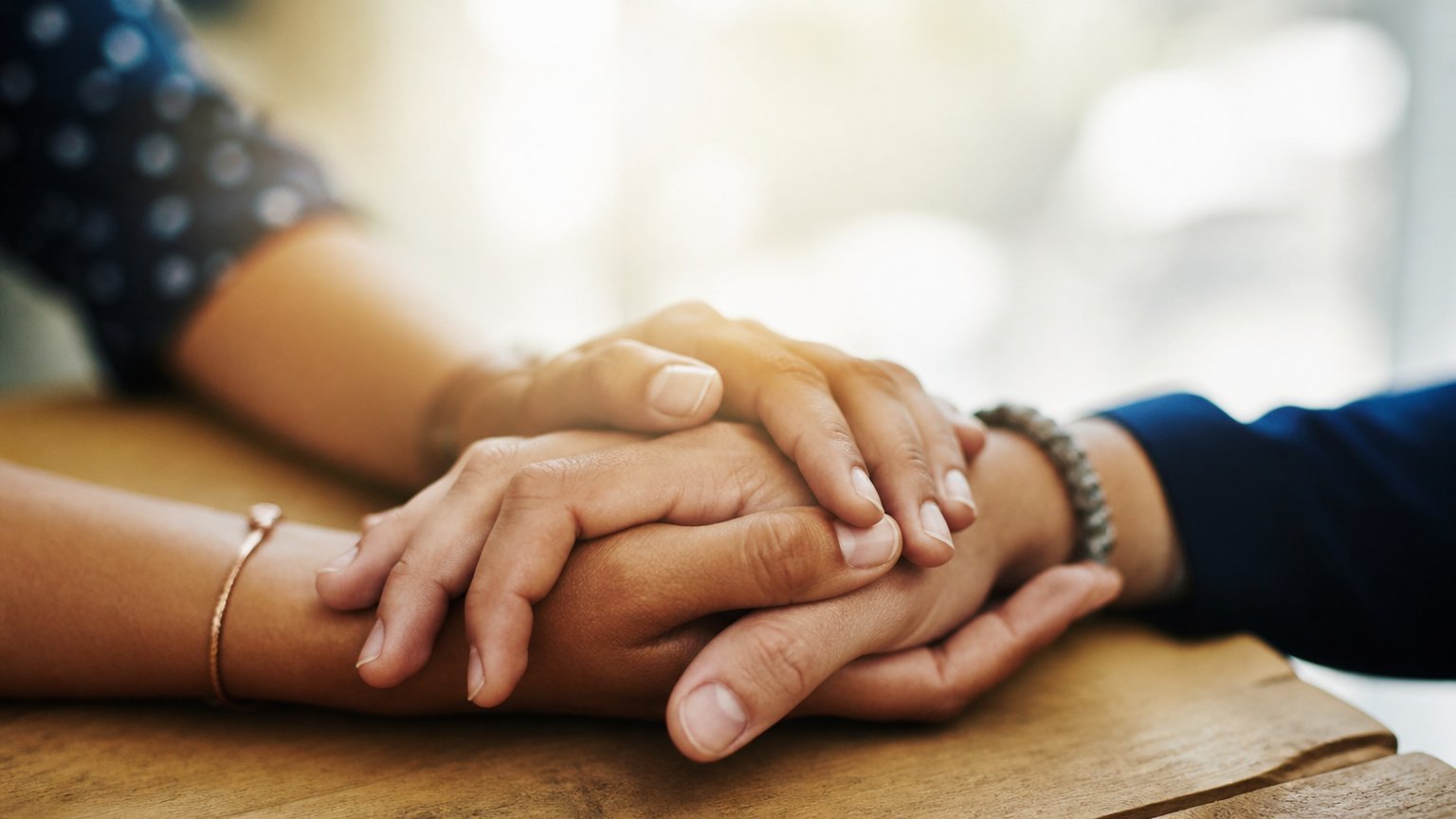 Two people holding hands in a close reassuring gesture, a sign of secure connection